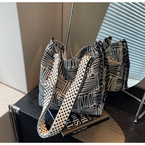 Detailed shot of the woven plaid tote bag with adjustable patterned wide strap and silver buckle