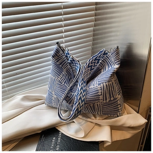 Close-up of blue and white woven canvas tote bag with wide strap on white cloth
