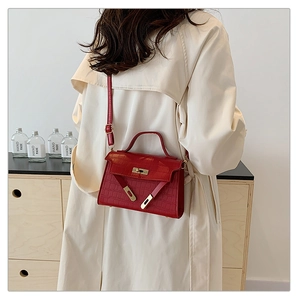 Detail of red crocodile pattern handbag with gold hardware and top handle strap