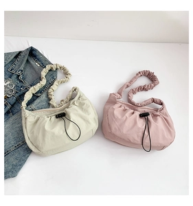 Detail of nylon gather shoulder bags in beige and pink with drawstring closures