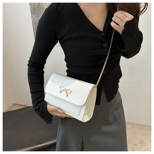 Détail du petit sac à main crème en similicuir avec nœud doré et bandoulière en chaîne