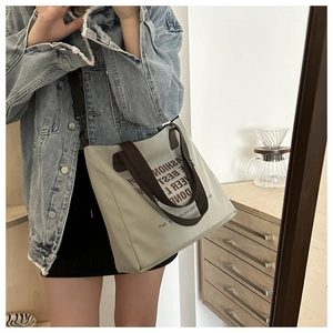 Détail du sac fourre-tout en toile vert clair avec anses brunes et bandoulière