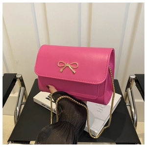 Vue détaillée du sac bandoulière rose fuchsia avec fermoir nœud doré et bandoulière chaîne