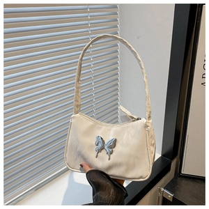 Close-up of a white hobo bag featuring a silver butterfly charm and textured fabric