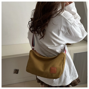 Detail of hobo bag showing mustard canvas texture and brown leather patch logo