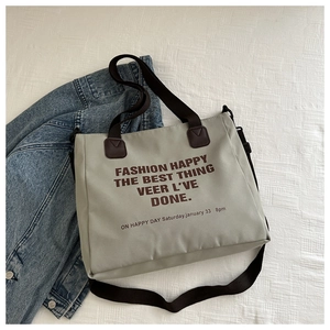 Détail à plat d'un sac cabas en nylon avec slogan et bandoulières réglables
