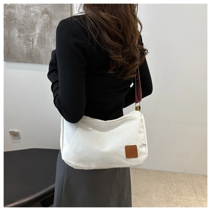 Detailed side view of white canvas crossbody bag featuring a wide red-brown shoulder strap