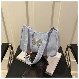 Detail of light blue pleated underarm bag with silver butterfly charm and wide strap