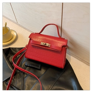 Detail of red crocodile texture small square bag with metal lock and single handle