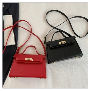 Detail view of mini crocodile pattern handbags in red and black with golden twist locks