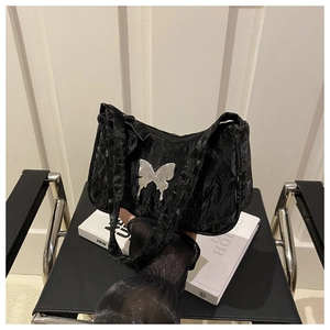 Detail of black pleated fabric handbag with silver metal butterfly ornament and zipper