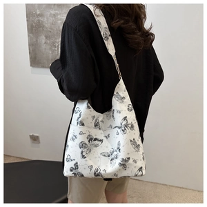 Detailed back view of a white tote bag with black butterfly prints worn on shoulder