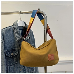 Detail of yellow canvas hobo bag featuring a colorful striped wide shoulder strap