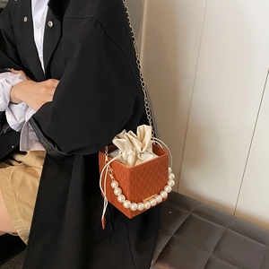 Orange woven mini box bag with pearl handle and gold chain strap on female model