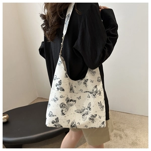 Detail of white leather tote bag with black butterfly print and exterior side pocket