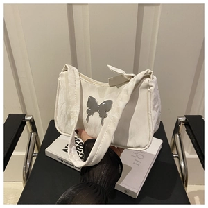 Detail of white pleated hobo bag featuring a large silver metal butterfly ornament