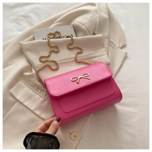 Vue détaillée du sac rose avec fermoir nœud doré et bandoulière en chaîne dorée