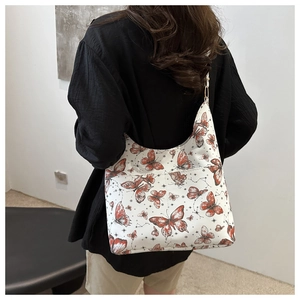 Close-up of white shoulder bag with butterfly print and gold metal ring details