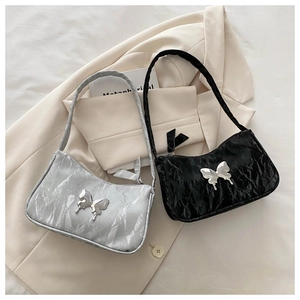 Detailed view of pleated silver and black shoulder bags with metal butterfly accents