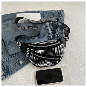Close-up of black crossbody bag with silver studs, patterned strap and daily essentials