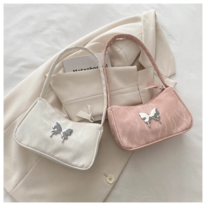 Close-up of ruched texture and silver butterfly ornament on pink and white handbags