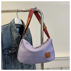 Detail of purple canvas crescent bag featuring a contrast colorful wide webbing strap