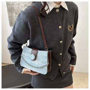 Détail du sac à bandoulière en denim bleu clair avec chaîne argentée et sangle en cuir