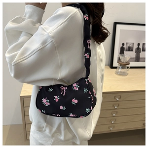 Sac hobo à imprimé floral avec des accents de nœud rose sur l'épaule du mannequin