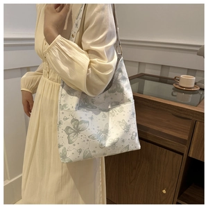 Detail of white tote bag featuring soft green butterfly prints and constellations
