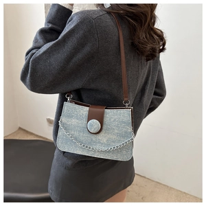 Détail du sac bandoulière en tweed bleu clair avec sangle en cuir brun et chaîne argentée