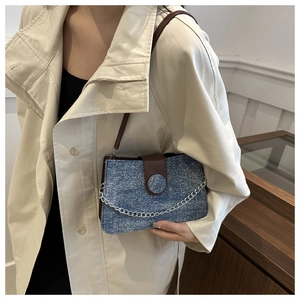 Détail du sac denim à paillettes bleues avec bandoulière en cuir marron et chaîne argentée