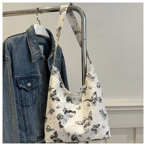 Detail of butterfly print tote bag with metal ring and front pocket hanging on hanger