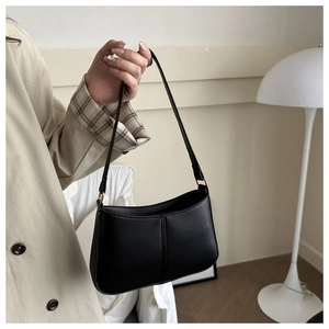 Sac hobo minimaliste en cuir noir avec détails dorés et coutures décoratives fines