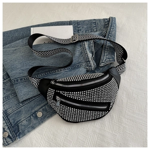 Detail of black crossbody bag with silver studs and V-shaped striped woven shoulder strap