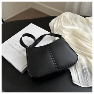 Détail d'un sac sous les aisselles en cuir noir minimaliste avec boucle dorée