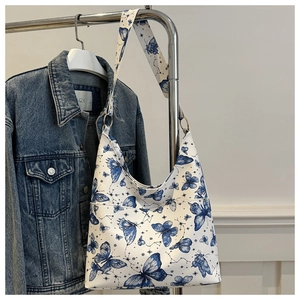 Detail of white tote bag with blue butterfly print and golden ring strap attachments