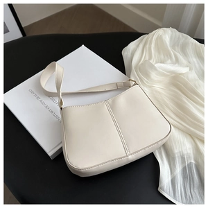 Gros plan sur le sac sous le bras minimaliste crème avec surpiqûres sur fond noir