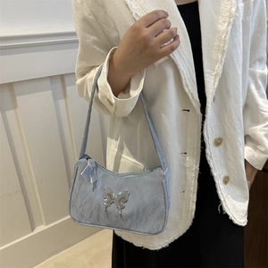 Chic blue-gray ruched underarm bag with silver metallic butterfly emblem on white suit