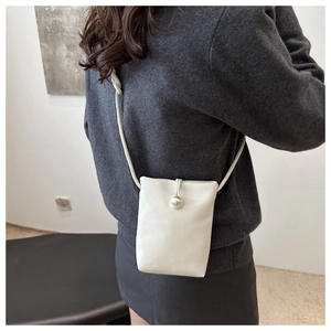 Gros plan du sac bandoulière blanc minimaliste avec un grand fermoir perle