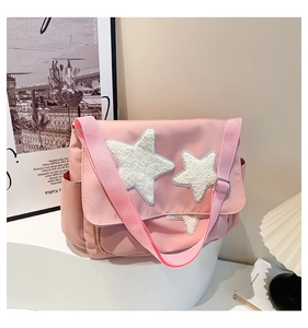 Detail of pink messenger bag featuring soft white plush star patches and side pocket