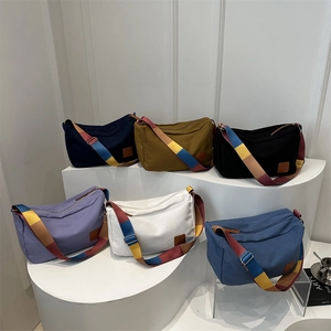 Canvas crossbody bags in six colors with rainbow wide straps on minimalist white stands
