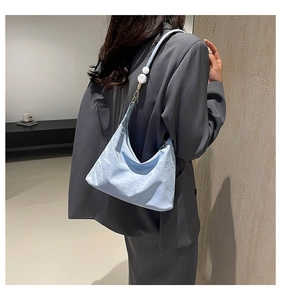 Detail of light blue hobo bag with white pearl strap accents on charcoal blazer