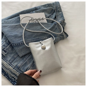 Détail du mini sac en cuir PU argenté avec fermoir perle sur fond en jean bleu