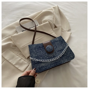 Detail of blue denim crossbody bag with star-like rhinestones and silver chain