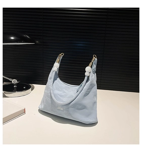 Detail of light blue pleated hobo bag with white bead charms and classic label