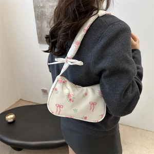 Sac hobo blanc à imprimé roses roses et nœuds porté par un mannequin de profil