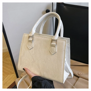 Detailed view of cream PU leather handbag with elegant pleated texture and gold hardware