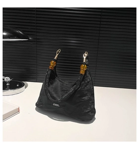 Detail of hobo bag with amber resin beads and gold hardware on pleated black fabric