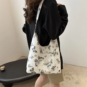 White butterfly print underarm tote bag with wide strap on model in minimal room
