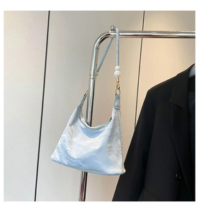 Detail of light blue cloud-print hobo bag with satin texture and pearl strap accessory